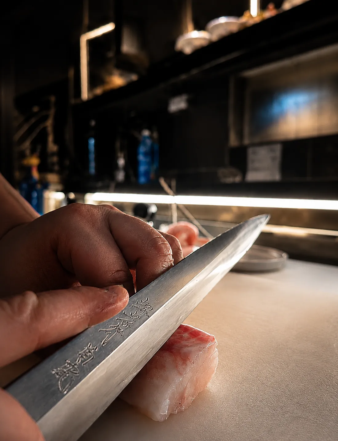 La lama giapponese dello chef incide un trancio di pesce sul tagliere