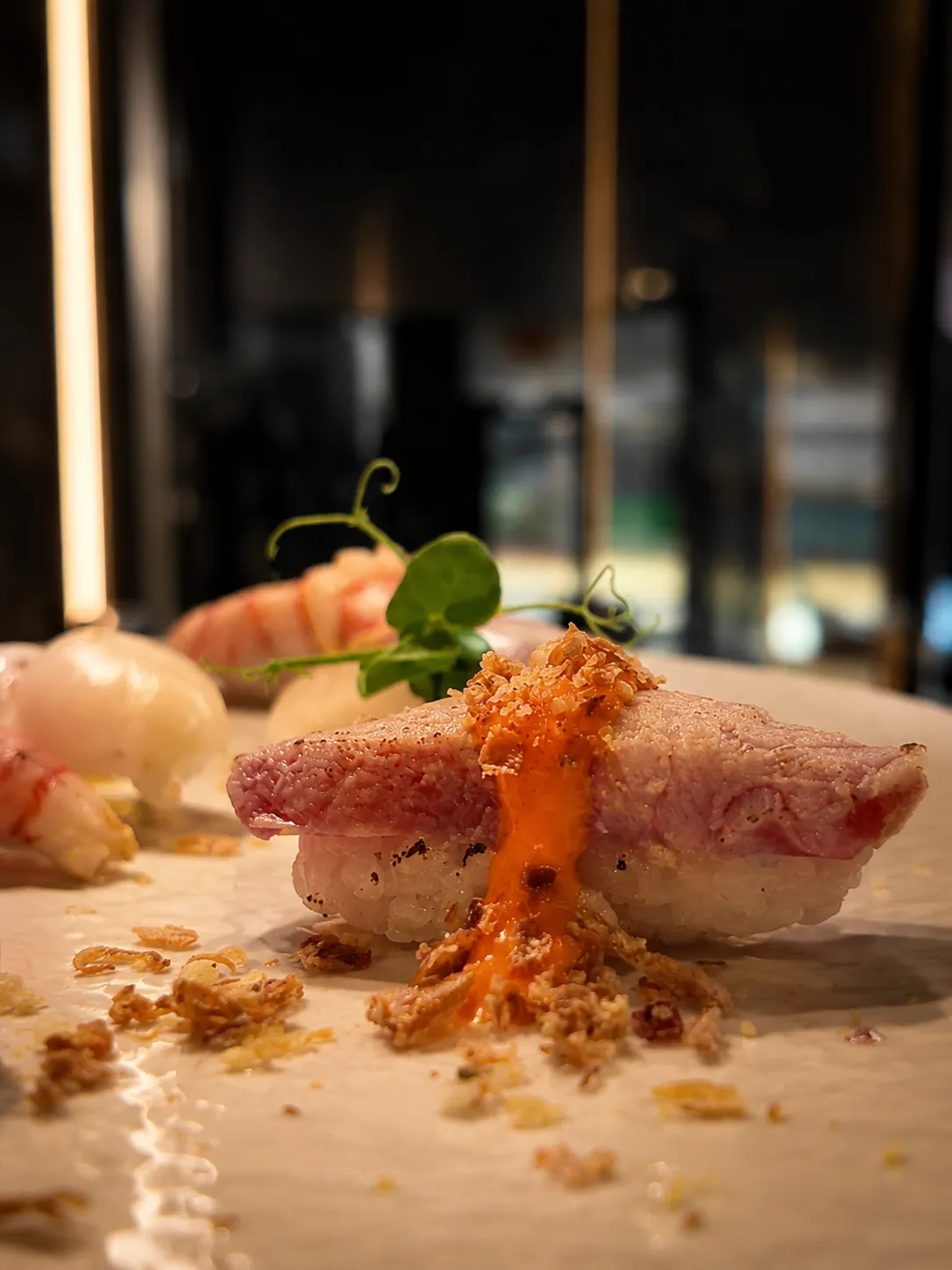 Nigiri scottato con salsa spicy in primo piano, bokeh caldo della sala