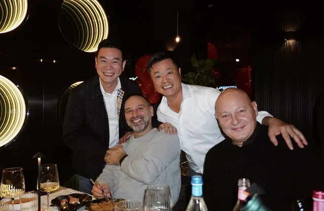 Quattro amici sorridenti abbracciati al tavolo di Yoshi
