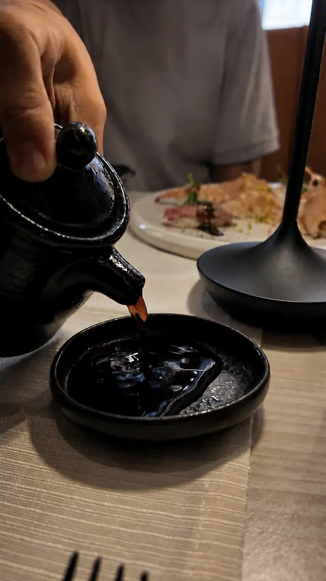 Salsa di soia versata da una teiera in ceramica nera