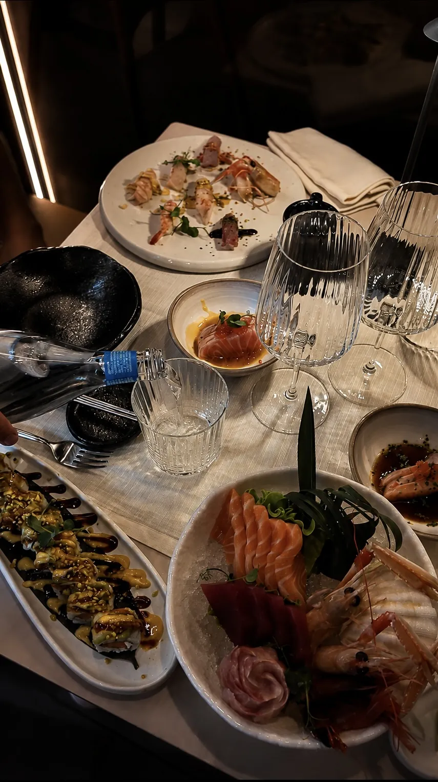 La tavola imbandita di Yoshi vista dall'alto: sashimi, roll e calici